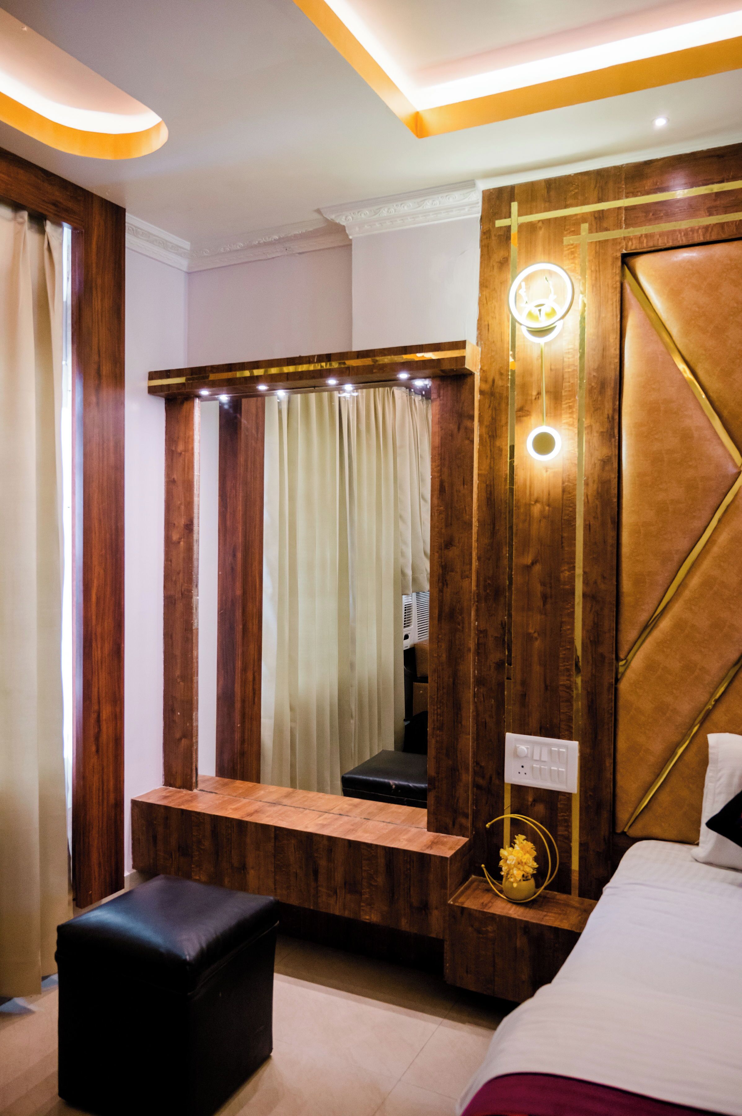A modern bedroom with a wooden vanity, a mirror, a bench, and a bed.
