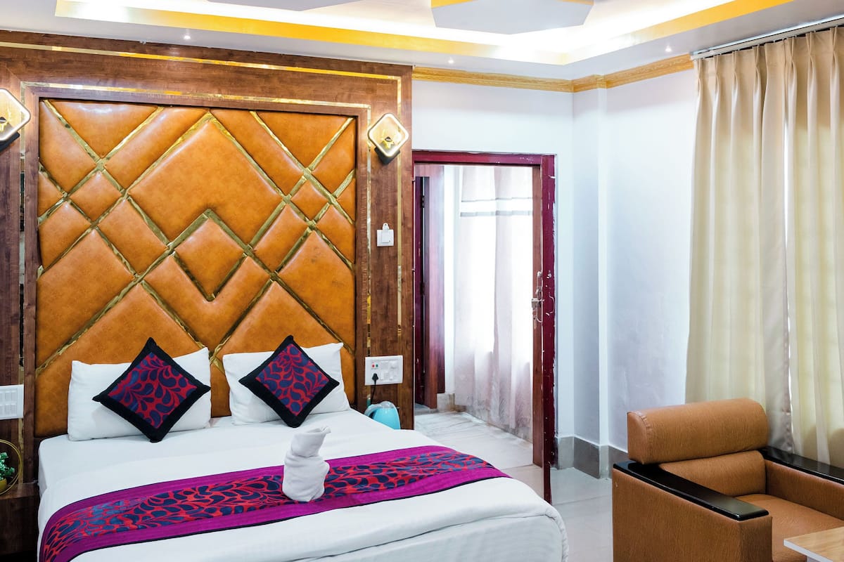 A modern hotel room with a large bed, a wooden headboard, and a ceiling fan.