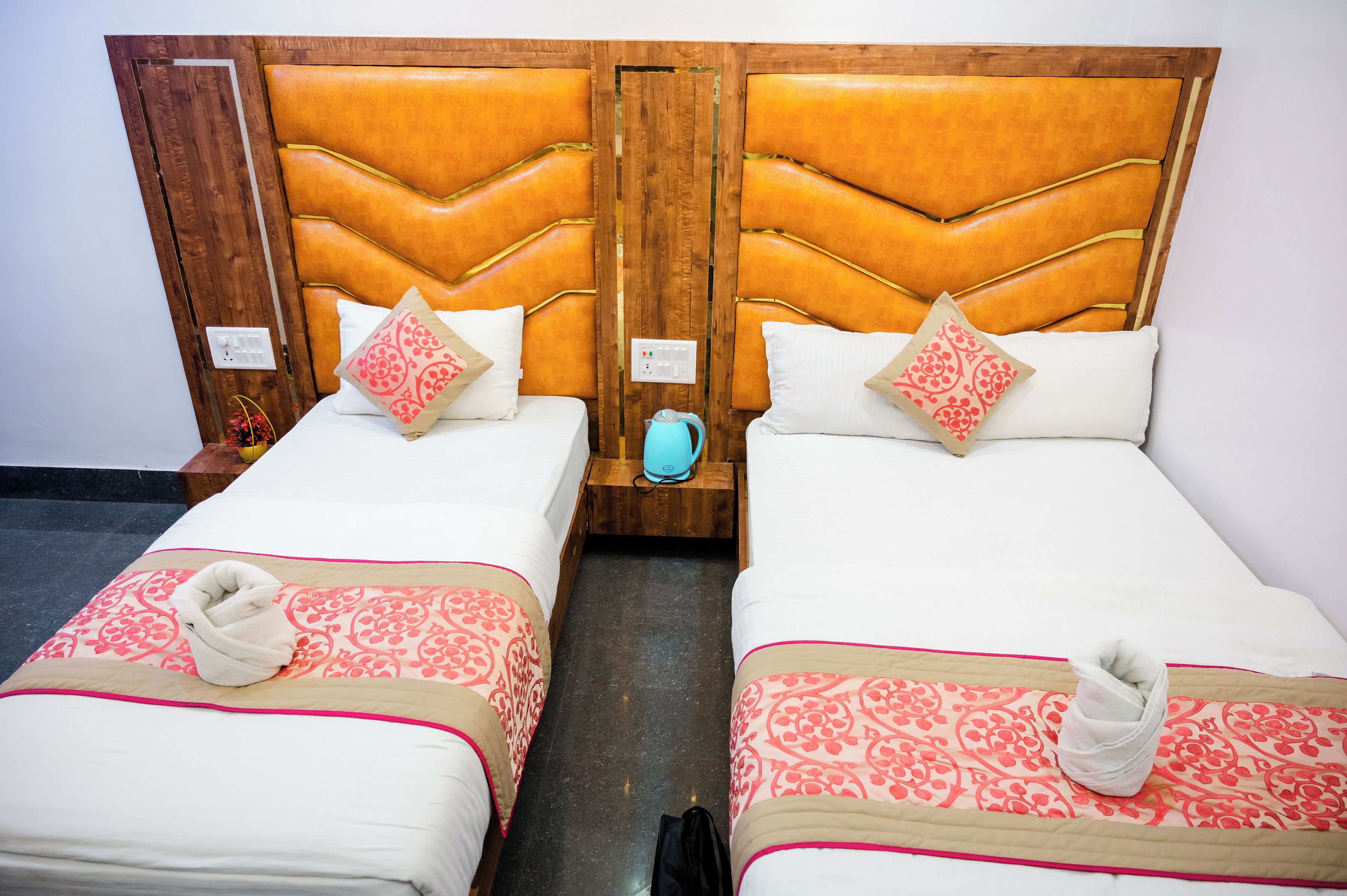 Two twin beds with matching headboards, white bedding, and pink patterned throw blankets.