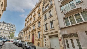 A street view of a row of classic European buildings with parked cars and a cobblestone road. - Appartment aux Champs-Elysées avec climatisation (Paris)