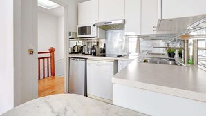 A modern kitchen with white cabinets, stainless steel appliances, and a dishwasher. - Appartment aux Champs-Elysées avec climatisation (Paris)