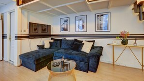 A living room with a sectional sofa, a glass coffee table, and a small side table with a vase.