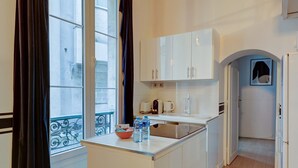 A compact kitchen with white cabinets, a small island, and a window with curtains.