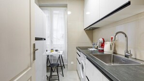 Una cocina compacta con lavadora, lavamanos y un pequeño comedor con mesa y silla.