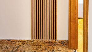 A wooden slat wall with the word "NAMASTE" carved into it, a wooden door frame, and a marble floor. - RentPlanet - Apartament Grabiszyńska (Wroclaw)