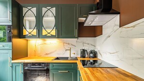 A modern kitchen with teal cabinets, a wooden countertop, and a built-in oven. - RentPlanet - Apartament Grabiszyńska (Wroclaw)