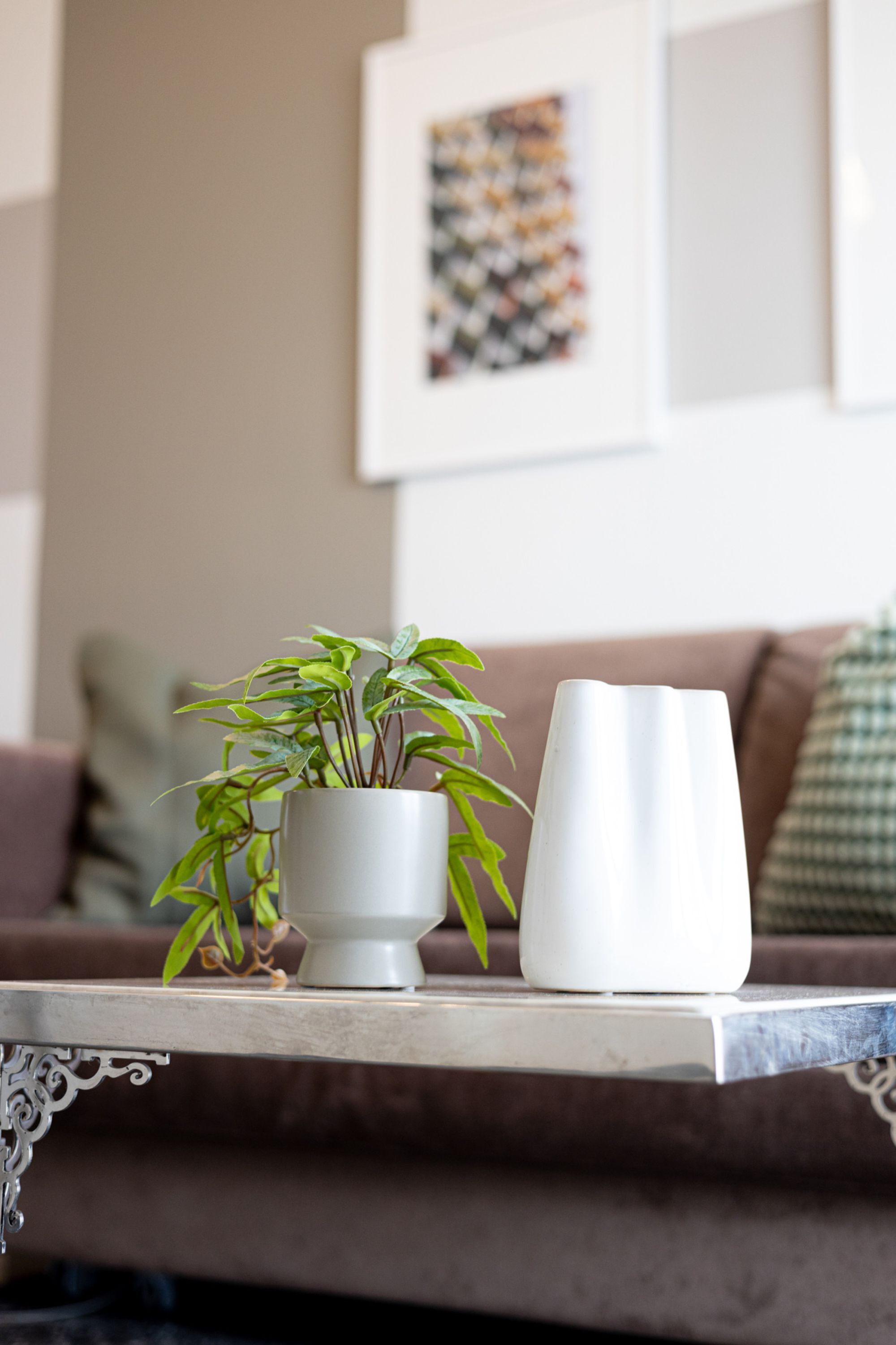 A living room with a white table, a potted plant, and a white vase.