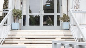 A building entrance with a double door, a staircase, and two potted plants. - Beachfront 2-bedroom Stay in Voula (Vari-Voula-Vouliagmeni)