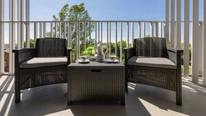 A balcony with two wicker chairs and a small table, featuring a white pitcher and cups. - Spacious Apartment in Wola | Parking | Balcony (Warszawa)