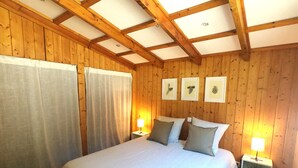Ein Schlafzimmer mit Holzwänden, einem Bett, zwei Nachttischlampen und drei gerahmten Bildern an der Wand.