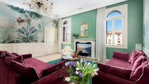 A living room with a large mural, a fireplace, and a view of buildings through a window.