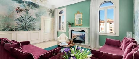 Un salón con un mural grande, una chimenea y vistas a edificios a través de una ventana.