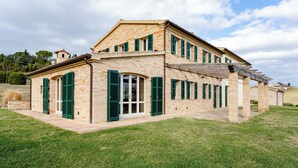 A two-story house with a brick exterior, green shutters, and a covered porch. - Elegant typical farmhouse with pool large wooded courtyard 10 minutes from Jesi (Marche)