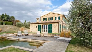 A two-story house with a wooden deck, a swimming pool, and outdoor seating. - Elegant typical farmhouse with pool large wooded courtyard 10 minutes from Jesi (Marche)