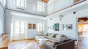 A spacious living area with a high ceiling, a balcony, and a dining area visible in the background. - Elegant typical farmhouse with pool large wooded courtyard 10 minutes from Jesi (Marche)