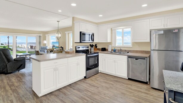 A modern kitchen with white cabinets, stainless steel appliances, and a large island.