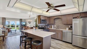 A modern kitchen with a central island, stainless steel appliances, and a ceiling fan.