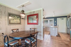 Ein Essbereich mit Holztisch und Stühlen, einer Hängeleuchte und einem gerahmten Bild an der Wand.