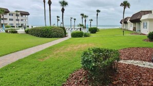 A resort with a pathway leading to a beach, surrounded by palm trees and well-maintained lawns. - Chateau by the Sea 12B Ocean View Retreat! (New Smyrna Beach)