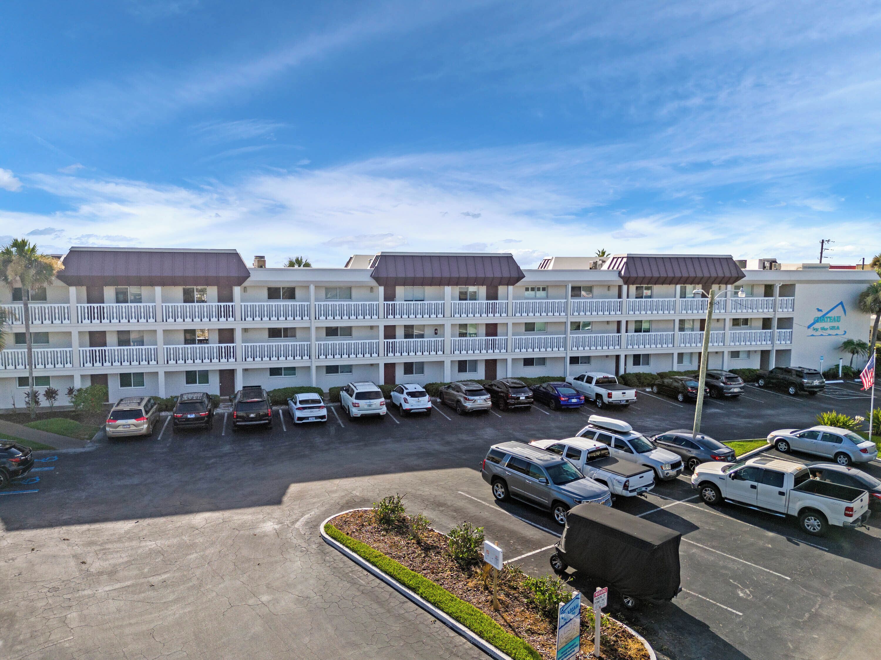 A multi-story motel with a parking lot filled with various vehicles.