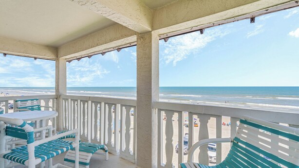 A balcony with a view of the beach, white railings, and green and white furniture. - Chateau by the Sea 34D Life's Better by the Sea! (New Smyrna Beach)