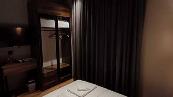 A hotel room with a bed, a desk, a mirror, and a wardrobe.