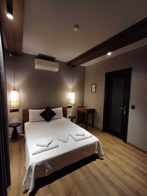 Una cama bien hecha con sábanas blancas, un cabecero de madera y dos mesitas de noche con lámparas.