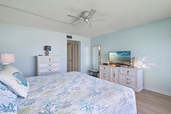 Une chambre à coucher avec un lit, une commode, un téléviseur et un ventilateur de plafond.