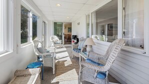 A covered porch with wicker furniture, a lamp, and a view into the house. - Recently updated home sleeping 10, steps to the beach! (Harwich Port)