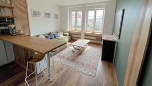 Moderni keittiö, jossa on puinen työtaso, baarituolit ja kahvinkeitin.