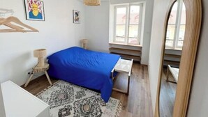 Makuuhuone, jossa on sänky, kissanleikkipuu, ikkuna ja peili.