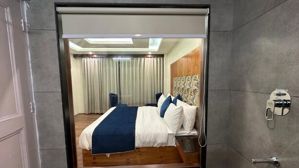 Una habitación de hotel moderna con una cama grande, un cabecero de madera y un espejo en la pared.