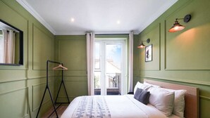 A bedroom with a bed, a hanging light, a window, and a view of the outside. - The Balham Hideout - Trendy 2bdr Flat (London)