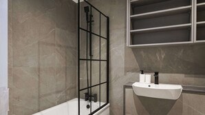 A modern bathroom with a bathtub, a glass-enclosed shower, and a white sink with a mirror. - The Balham Hideout - Trendy 2bdr Flat (London)