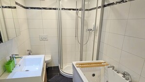 A modern bathroom with a freestanding bathtub, a shower enclosure, and a vanity with a sink. - Luxury Apartment Garden (Brienz)