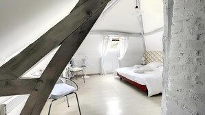 A bedroom with a sloped ceiling, a bed, a bedside table, a chair, and a window with curtains. - 2 Bedroom Bed & breakfast in Hucqueliers (Hucqueliers)