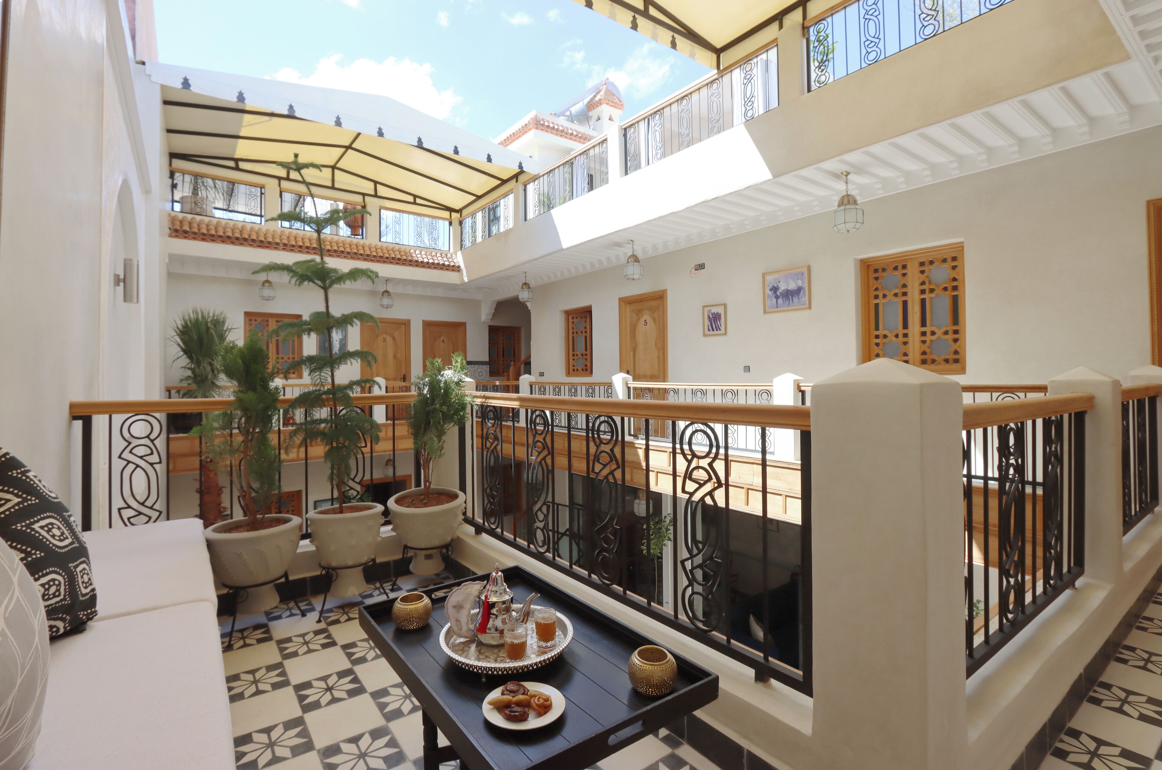 A spacious indoor area with a balcony, potted plants, a dining table with a tray of food, and a sofa.