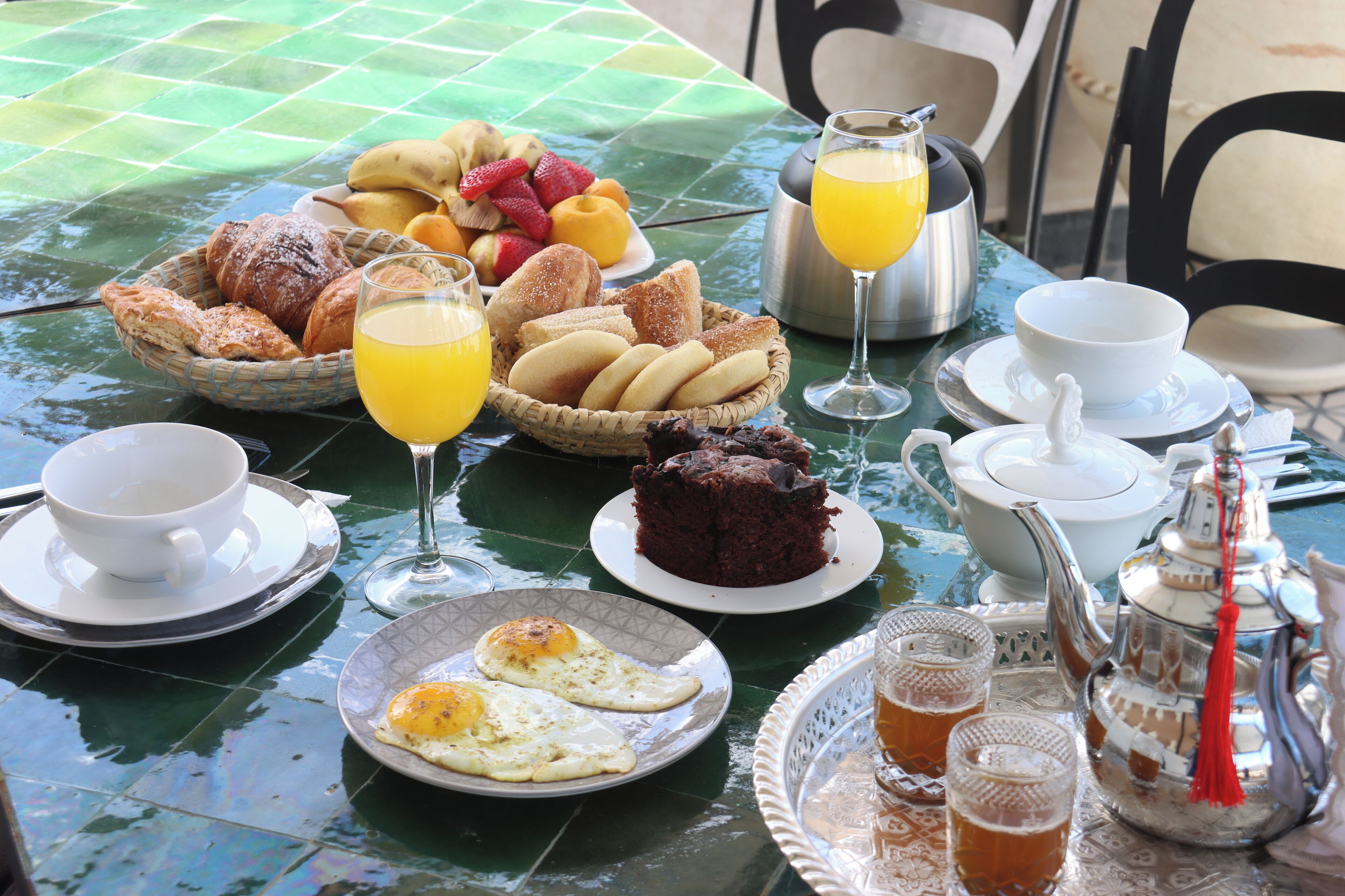A breakfast table with various foods, drinks, and tea set.