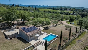 Une villa avec piscine, panneaux solaires et vue sur la campagne.