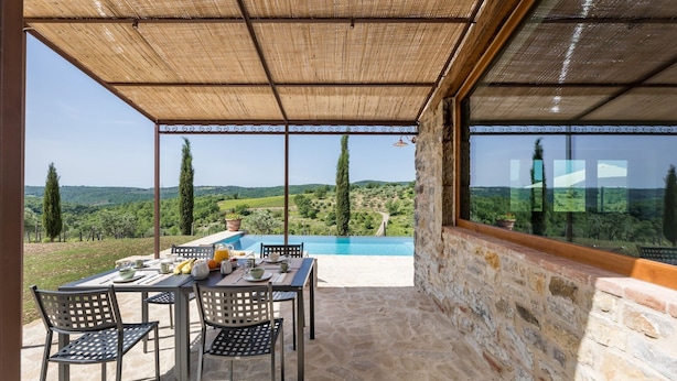 Une terrasse avec une table et des chaises, une piscine et une vue sur la campagne.
