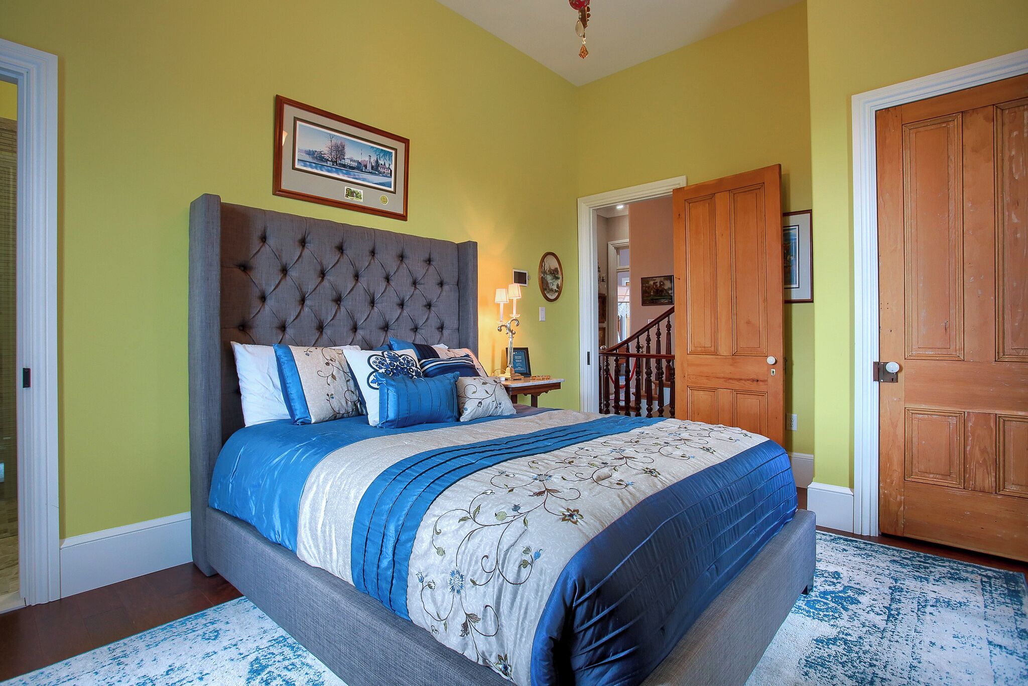 A bedroom with a large bed, a headboard, a nightstand, and a door.