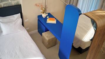 A hotel room with a bed, a blue nightstand with a vase of flowers, and a wooden headboard.