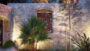 Un edificio de piedra con una puerta metálica decorativa y una palmera frente a él.