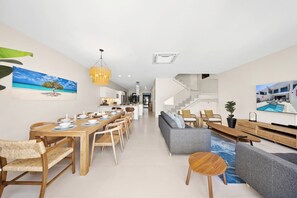 A modern interior with a dining area, sofa, and staircase.