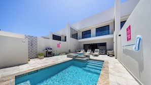 A modern outdoor swimming pool area with a clear blue pool, a barbecue setup, and a seating area with lounge chairs. - Walk to Beach: 4BR Oasis w/ Pool, Spa, View (Noord)