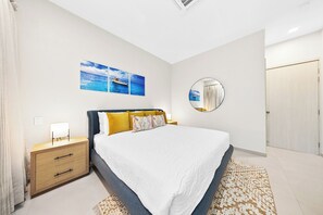 A bedroom with a bed, a bedside table, a mirror, and wall art.