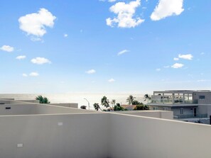 Eine Dachterrasse mit Blick auf das Meer und Palmen.
