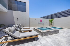 A rooftop terrace with a pool, lounge chairs, and a potted plant.