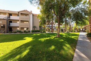 A residential building with a flat roof, multiple balconies, and a well-maintained lawn.