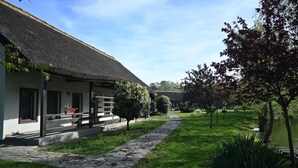 A traditional building with a thatched roof, a stone pathway, and a well-maintained lawn. - Egreta By Hoxton (Murighiol)